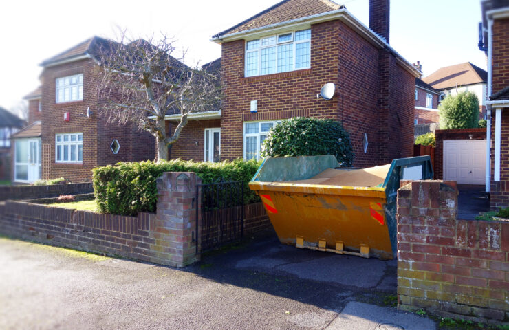 An image of a yellow skip in the driveway of a house.