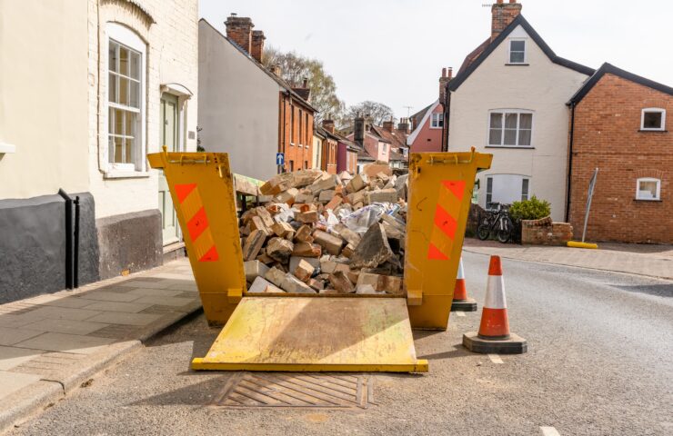 An image of a open skip, full with rubbish, with cones around it.