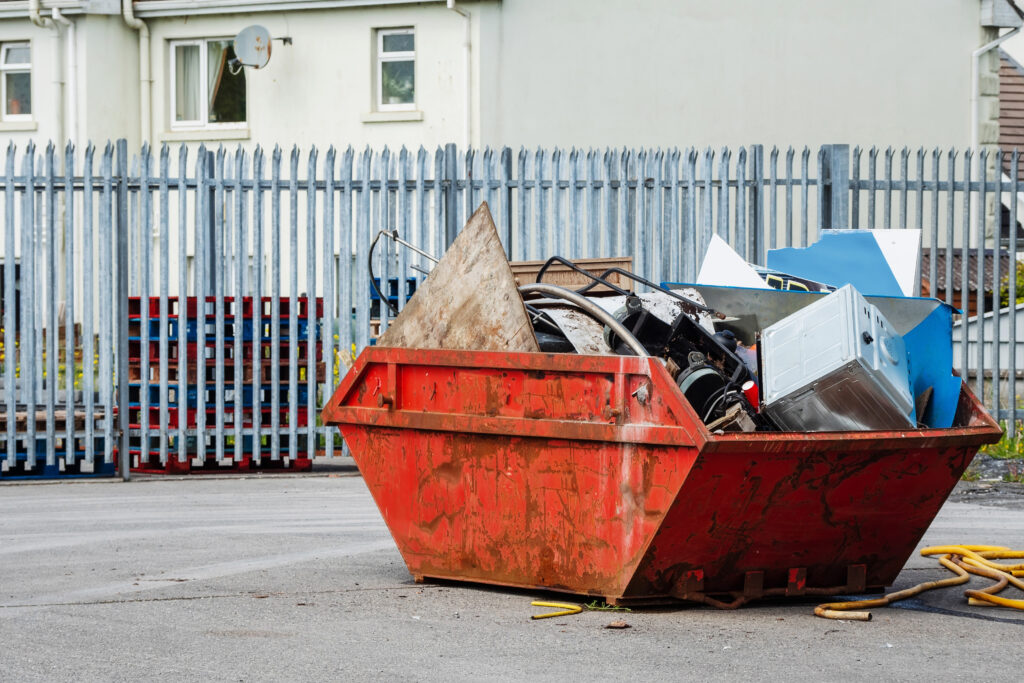 An image of a red skip, full of rubbish on a worksite.