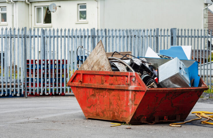 An image of a red skip, full of rubbish on a worksite.