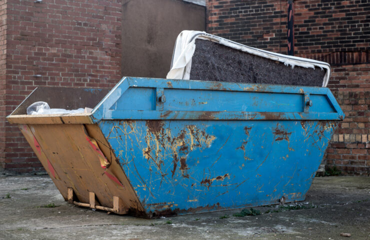 A blue skip with a mattress inside it.