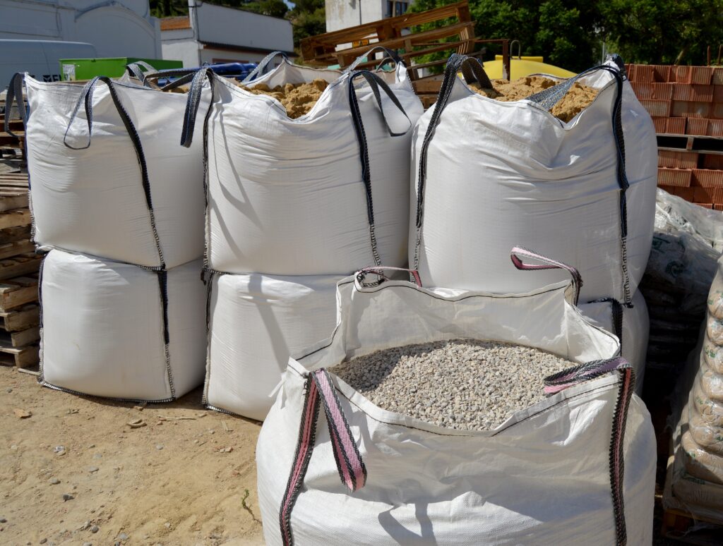Seven large white bags filled with aggregate, stacked on eachother.