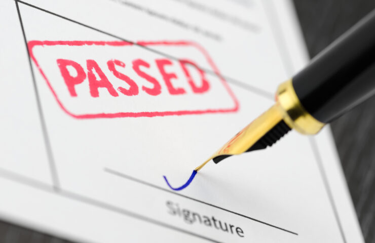 A close up of a skip permit with a fountain pen and a passed stamped on the document.