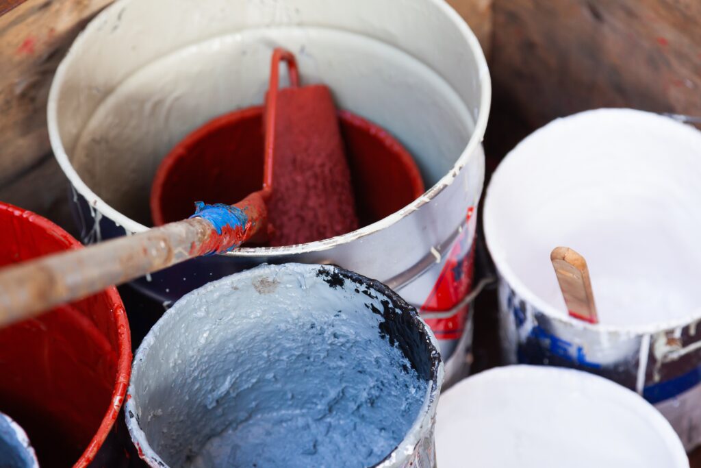 A collecyion of paint buckets with paint inside them.