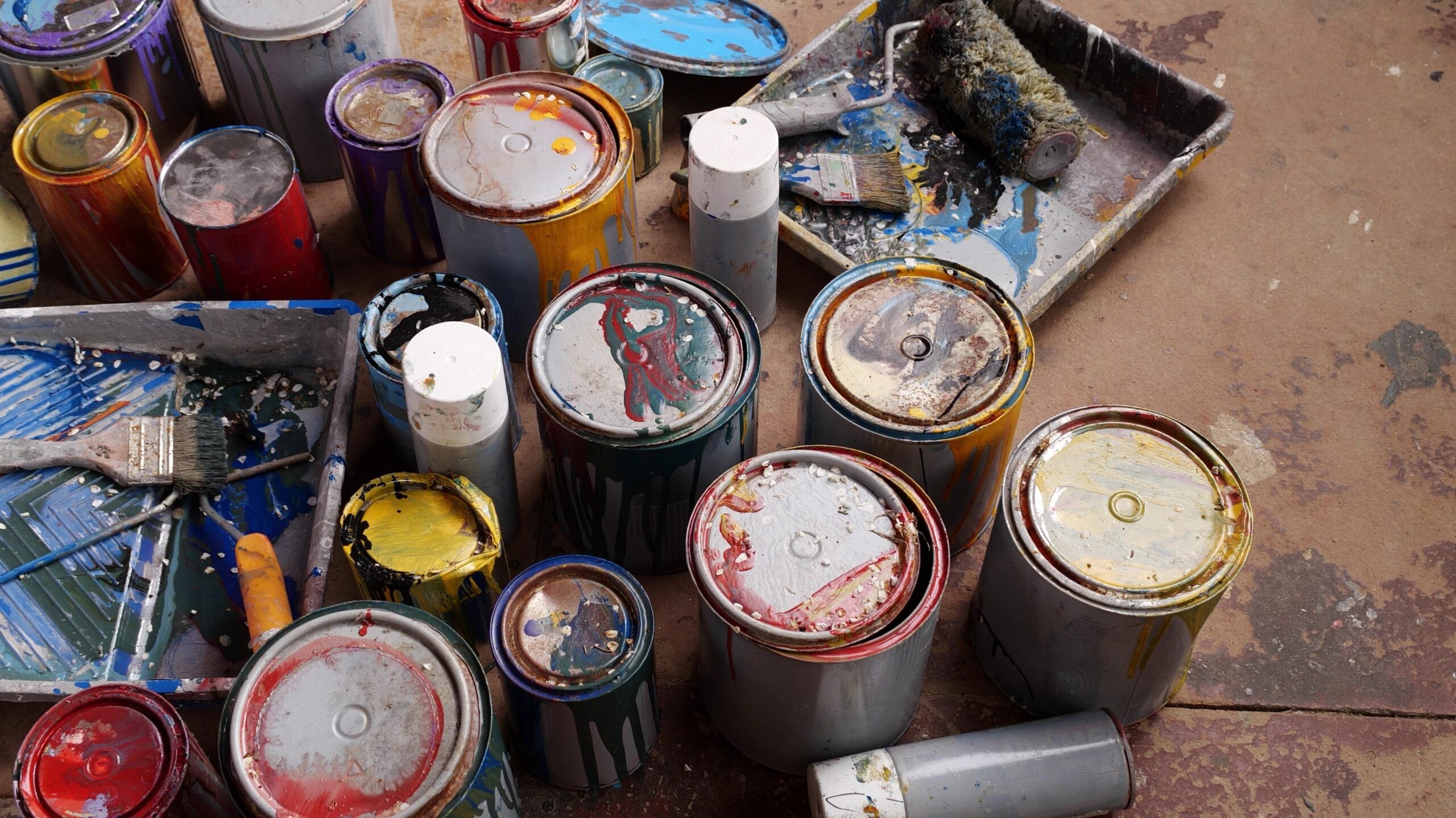 A bunch of old paint cans on the floor.
